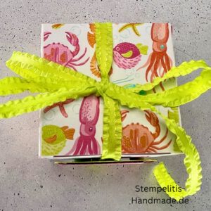 Handdekorierte Geschenkschachtel mit Schleife von oben, Geschenkschachtel mit liebevollem Aufkleber “Mit viel Liebe verschenkt”, Detailansicht Schleife auf Geschenkschachtel, Seitenansicht Geschenkschachtel mit buntem Designpapier, Offene Geschenkbox zum Befüllen, Geschenkschachtel auf hellem Hintergrund mit Dekorband, Handgemachte Geschenkverpackung mit grünem Band und Etikett